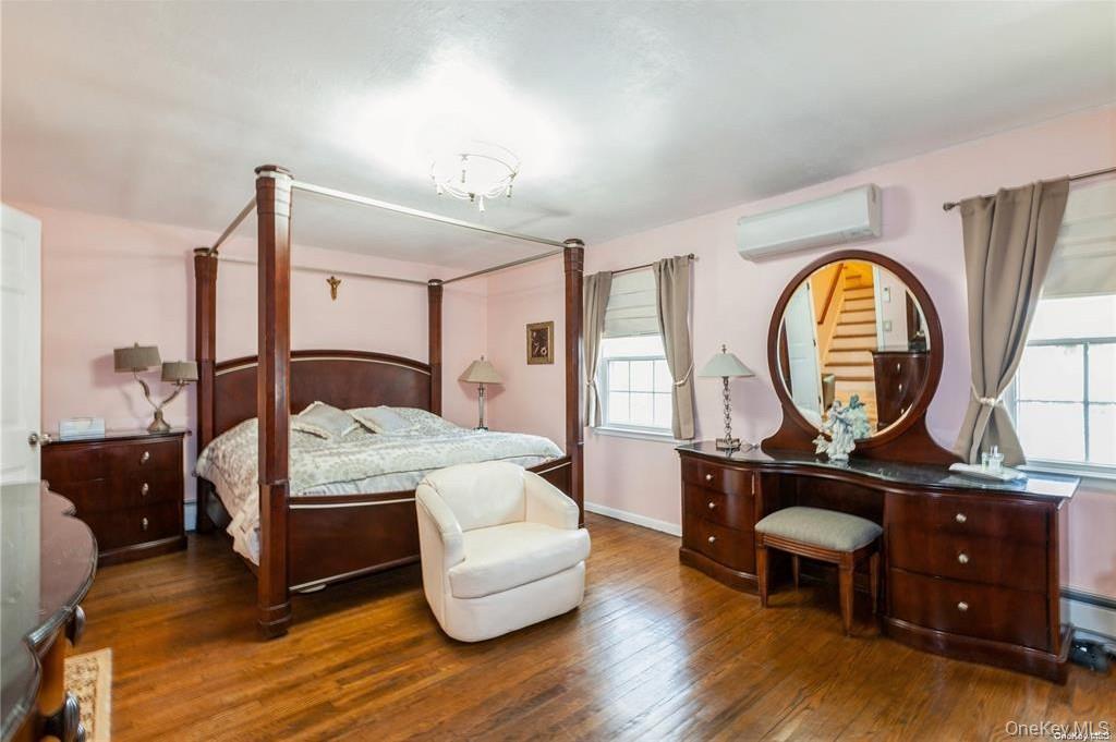 77 Duck Pond Road Glen Cove, NY 11542 - Photo 21 of 35 a bedroom with a bed a mirror on dresser and a chandelier
