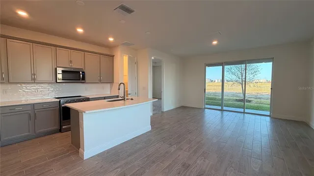 a large kitchen with wooden floors and stainless steel appliances