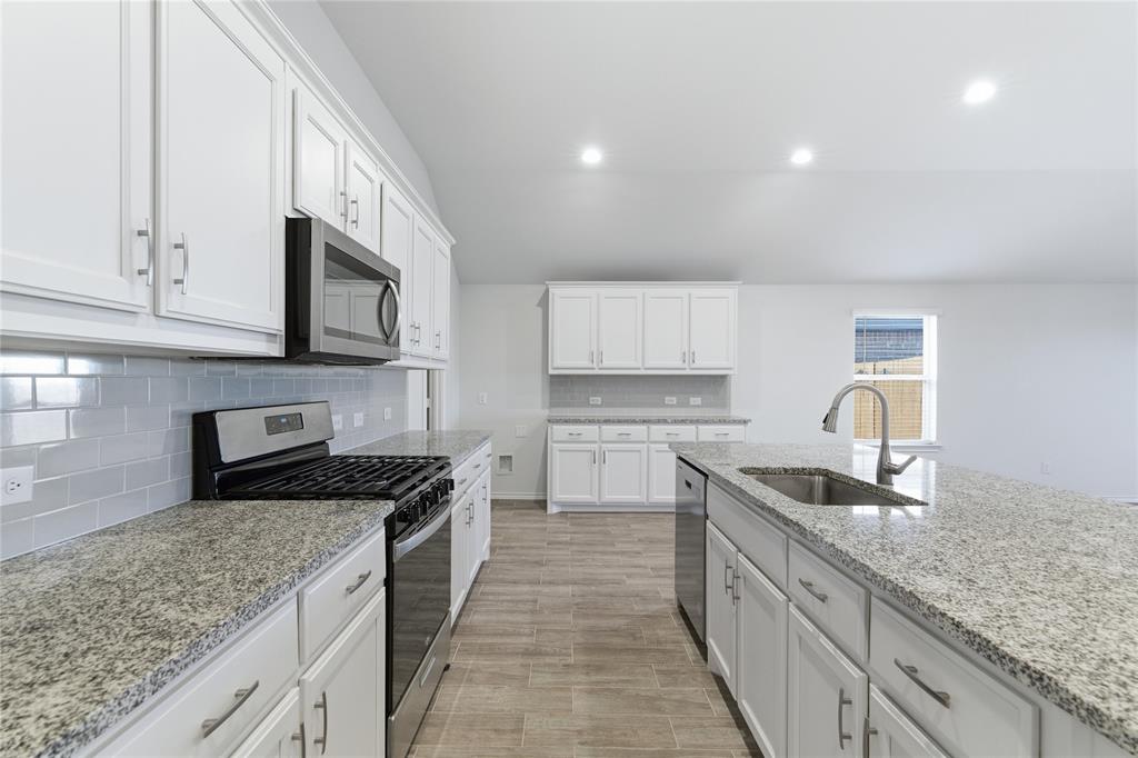 748 Ruellia Street Weatherford, TX 76086 - Photo 15 of 37 a kitchen with kitchen island granite countertop a sink and stove top oven