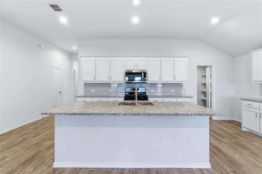 748 Ruellia Street Weatherford, TX 76086 - Photo 17 of 37 a kitchen with granite countertop a sink and a white cabinets