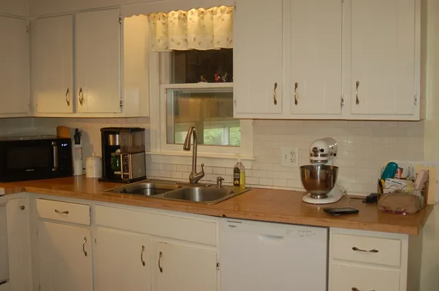 a kitchen with stainless steel appliances granite countertop white cabinets and a sink