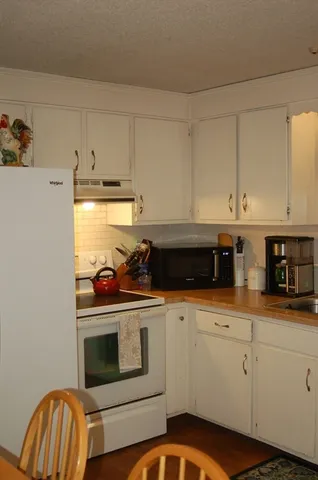 a kitchen with granite countertop white cabinets and white appliances