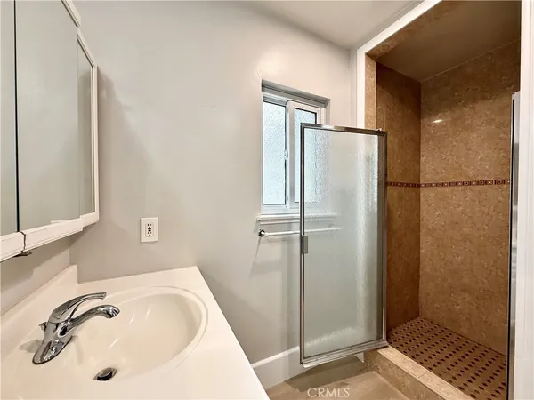 a bathroom with a granite countertop sink a mirror and a shower