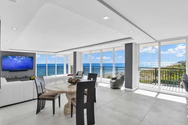 a living room with furniture a floor to ceiling window and flat screen tv