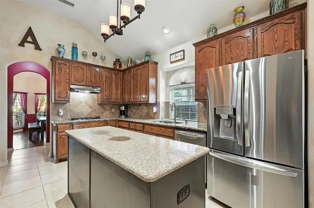 a kitchen with stainless steel appliances granite countertop a refrigerator a sink and a stove