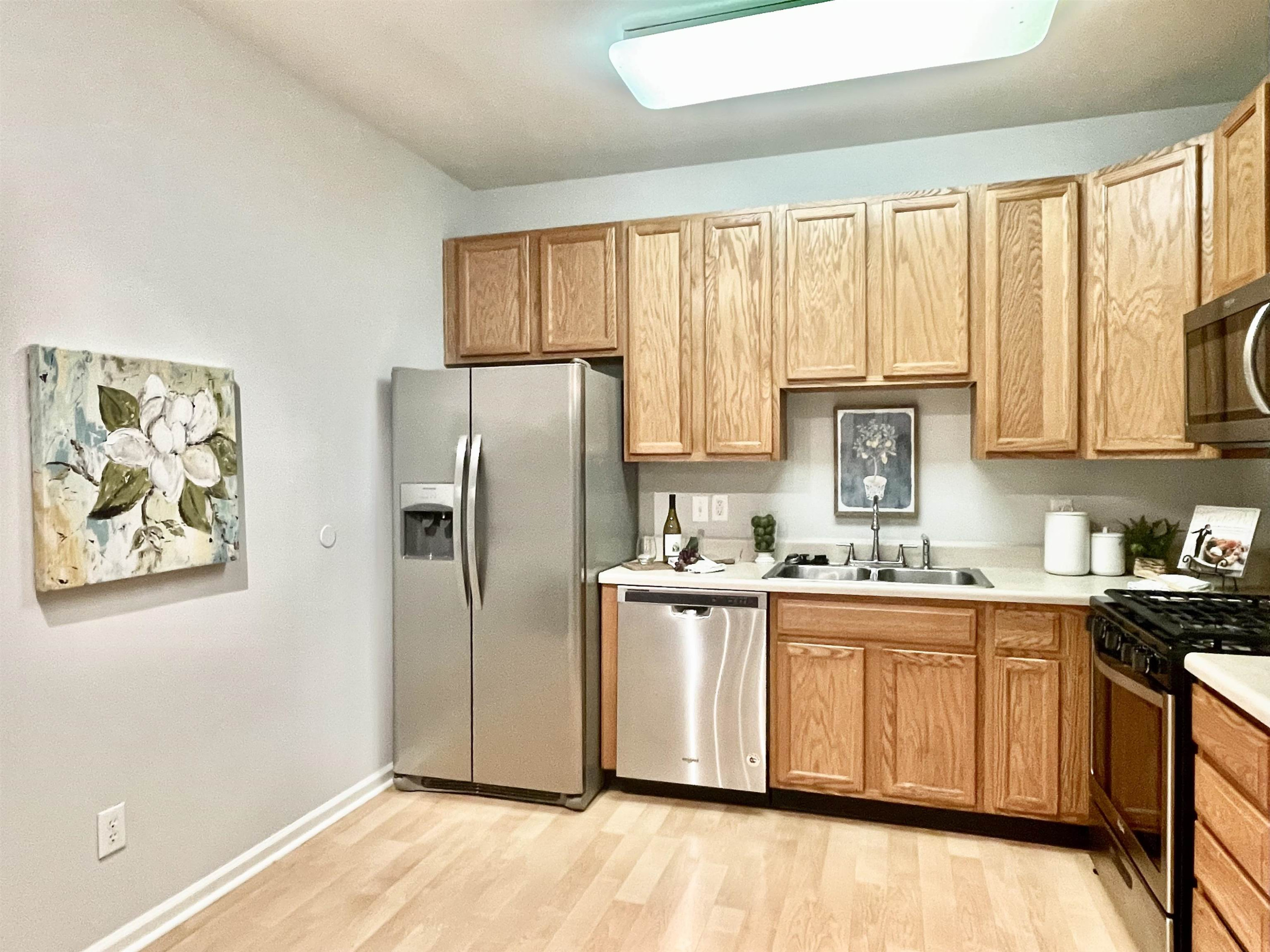 8621 Neuse Club Lane, Unit 109 Raleigh, NC 27616 - Photo 6 of 21 a kitchen with stainless steel appliances granite countertop a refrigerator a sink a stove and white cabinets with wooden floor