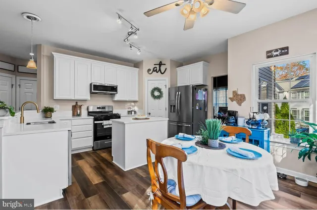 a kitchen with stainless steel appliances granite countertop a refrigerator a microwave oven a sink dining table and chairs with wooden floor