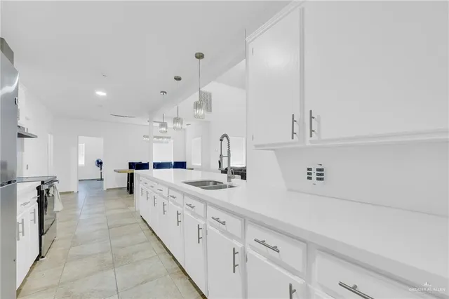 a large white kitchen with kitchen island a sink a stove and white cabinets