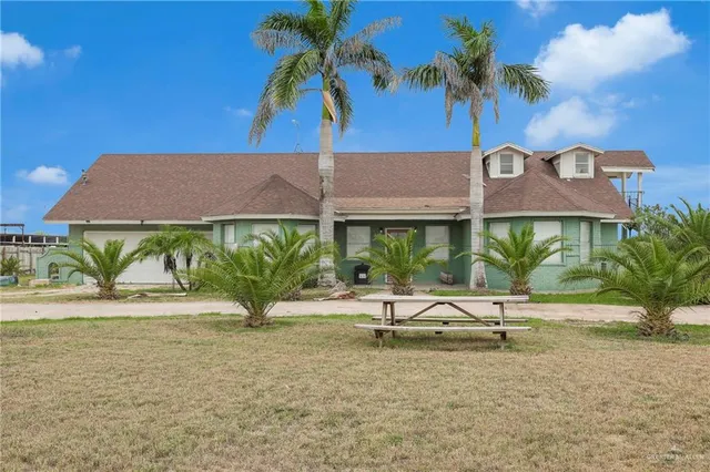 a view of front of house with a yard and potted plants