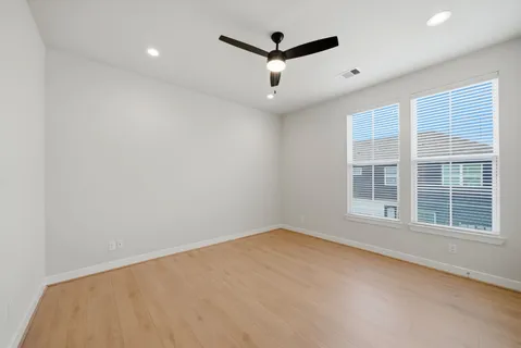 an empty room with ceiling fan and windows