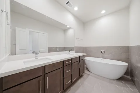 a spacious bathroom with a double vanity sink mirror and bathtub