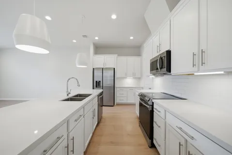 a kitchen with stainless steel appliances granite countertop a sink a stove and a refrigerator