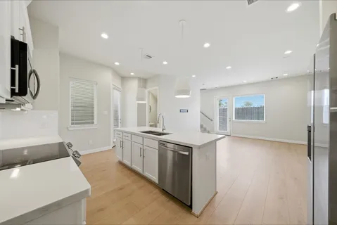 a large kitchen with stainless steel appliances kitchen island a large counter top and a wooden floors