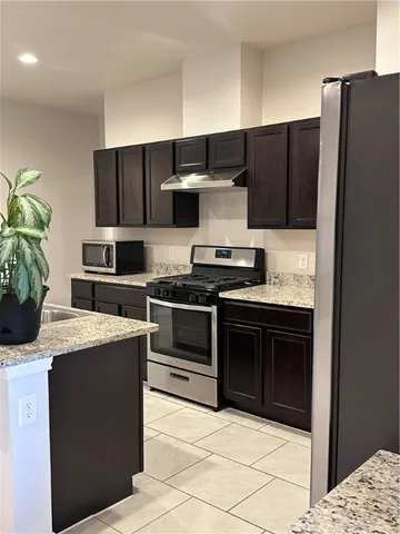 a kitchen with stainless steel appliances kitchen island granite countertop a refrigerator and a sink