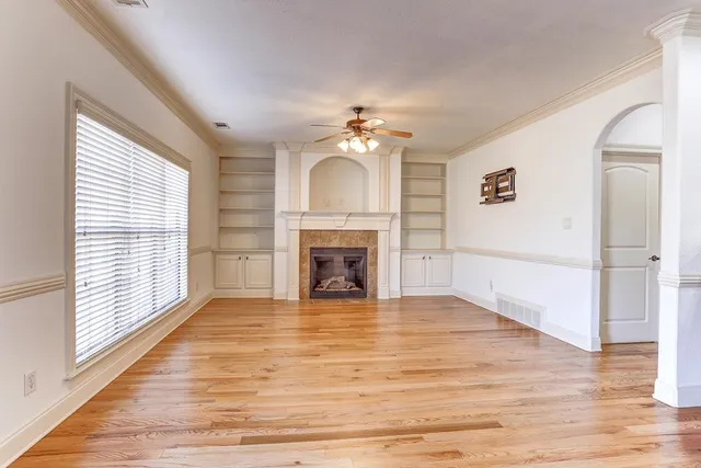 a view of a livingroom with a fireplace a ceiling fan and windows