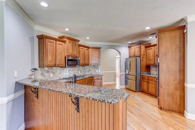 a kitchen with stainless steel appliances granite countertop a refrigerator a sink and a stove