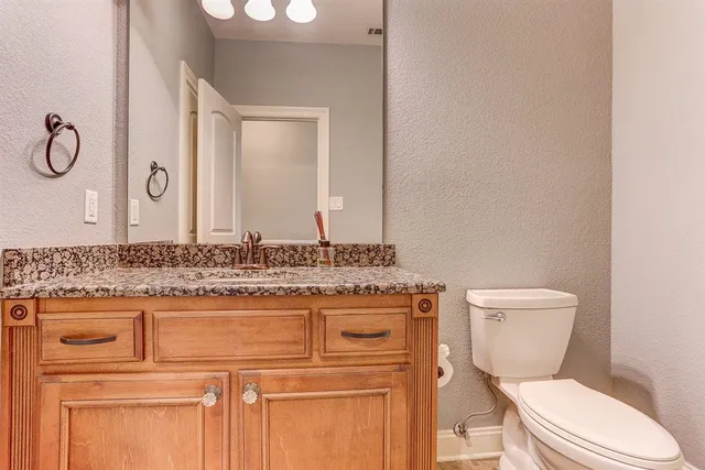 a bathroom with a granite countertop toilet sink and mirror