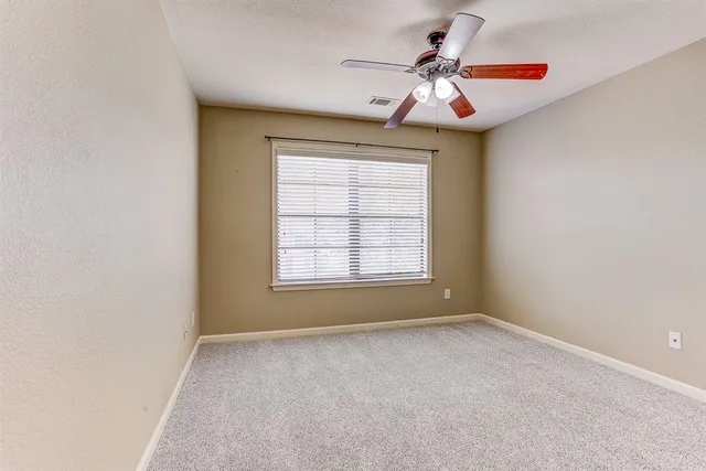 an empty room with a window and a ceiling fan