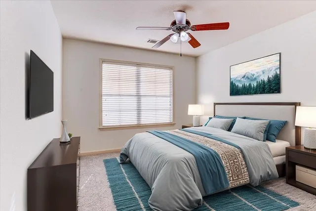 an empty room with a chandelier fan and windows