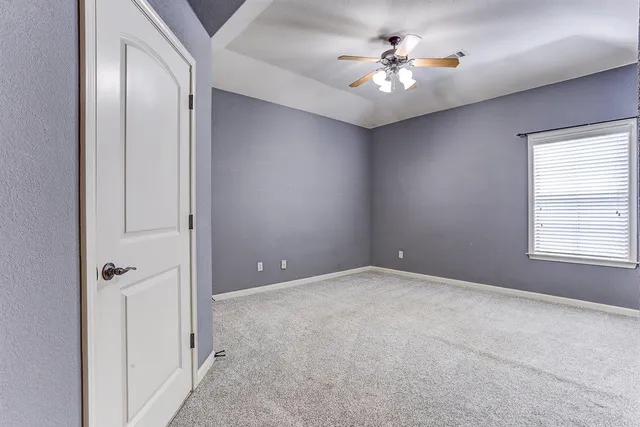 an empty room with windows and ceiling fan