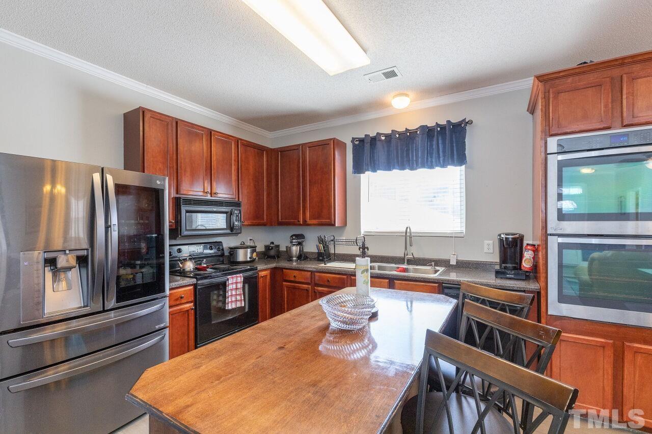 6012 Ladish Lane Raleigh, NC 27610 - Photo 11 of 29 a kitchen with granite countertop a stove a sink a refrigerator a dining table and chairs