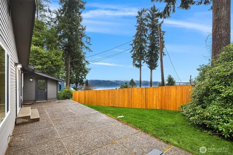 a view of backyard with large tree and wooden fence