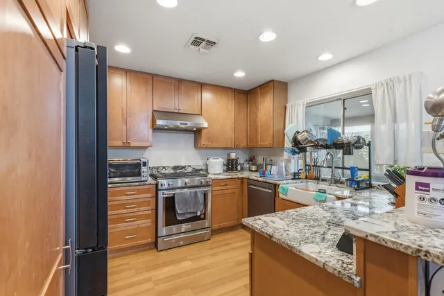 a kitchen with stainless steel appliances granite countertop a sink stove and refrigerator