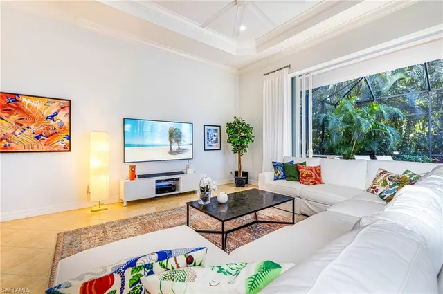a living room with furniture floor to ceiling window and a flat screen tv