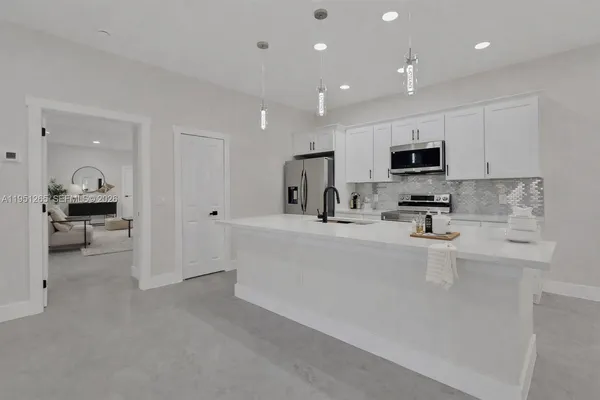 a large white kitchen with kitchen island a sink a stove and a refrigerator