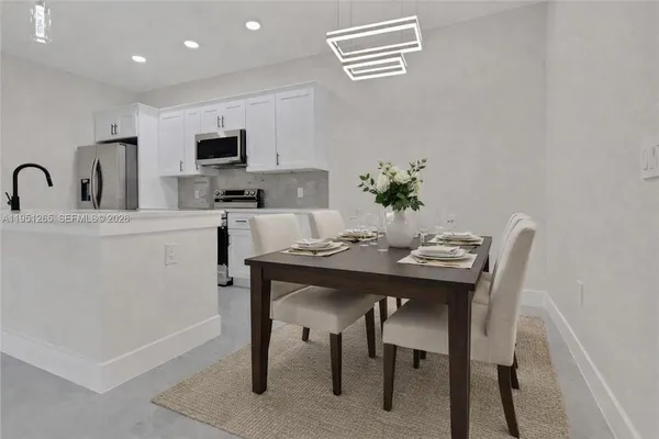 a kitchen with stainless steel appliances granite countertop a dining table and chairs