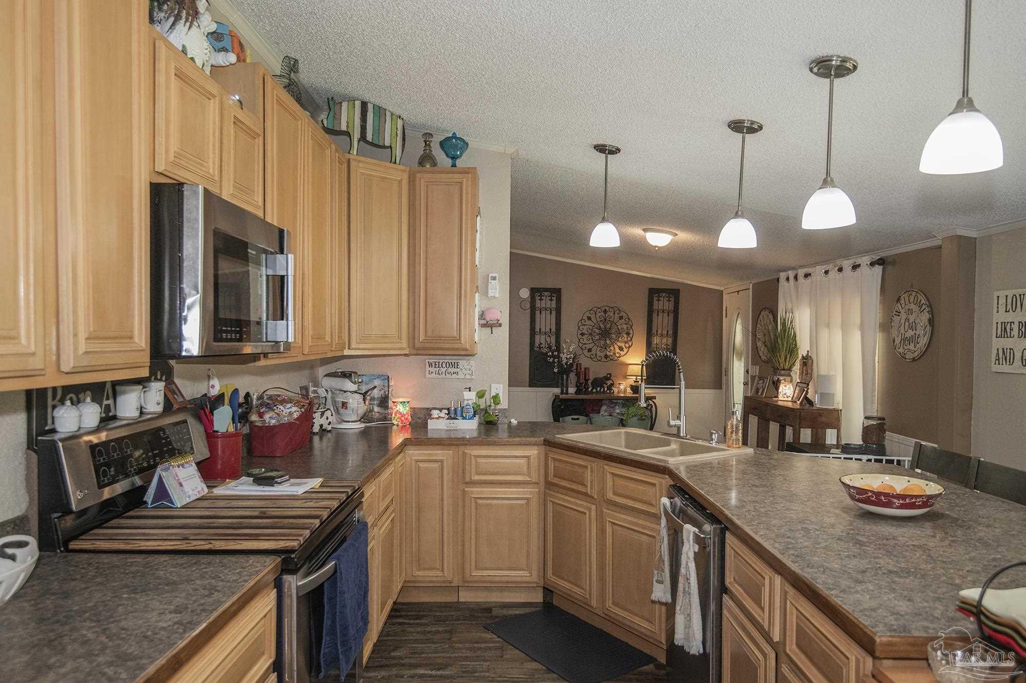 6739 Deception Road Milton, FL 32583 - Photo 8 of 24 a kitchen with stainless steel appliances granite countertop a sink a stove and a wooden cabinets