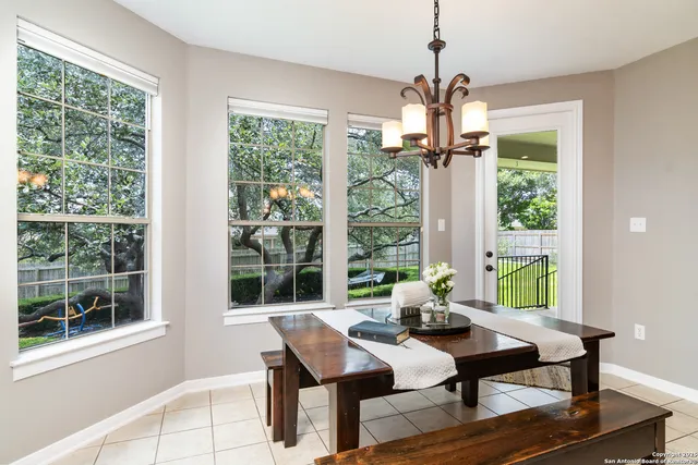 a dining room with wooden floor a chandelier a glass table and chairs