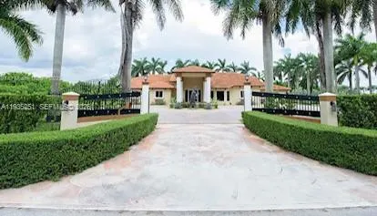 a front view of a house with a garden and palm trees