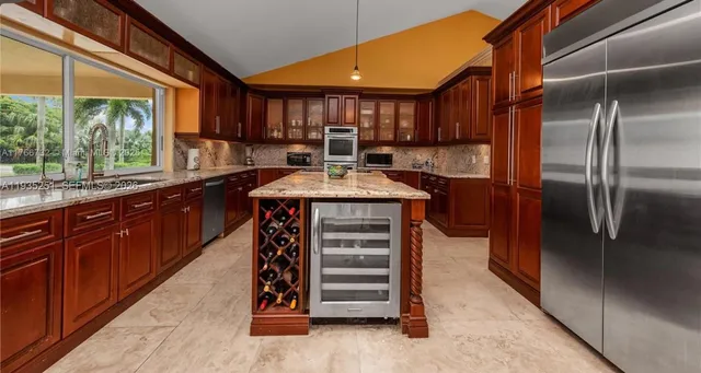 a kitchen with stainless steel appliances kitchen island granite countertop a refrigerator and a sink