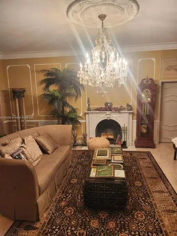 a living room with furniture a chandelier and a fireplace