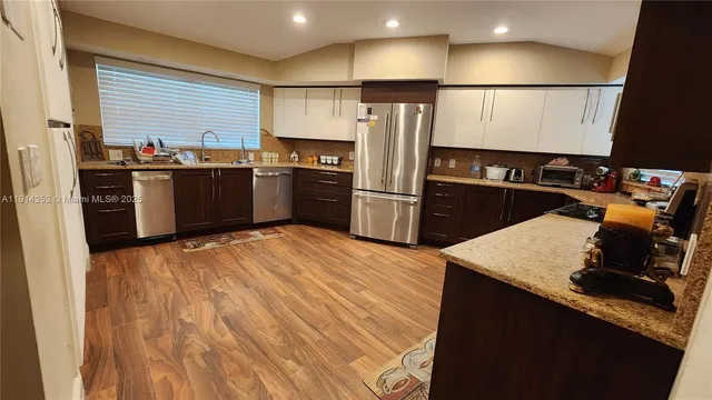 a kitchen with stainless steel appliances kitchen island granite countertop a refrigerator a sink and a stove