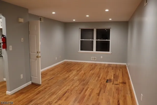 a view of an empty room with wooden floor and windows