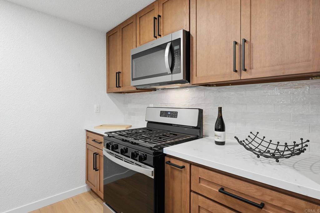1333 Helix Street Spring Valley, CA 91977 - Photo 16 of 45 a kitchen with granite countertop cabinets stainless steel appliances and wooden floor