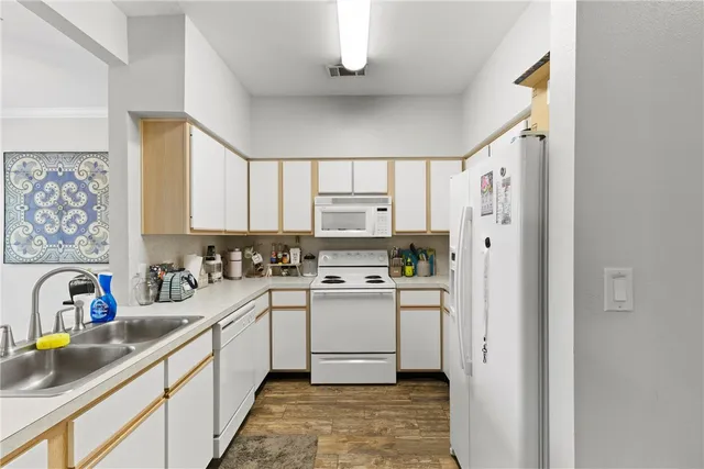 a kitchen with a sink appliances cabinets and a large window