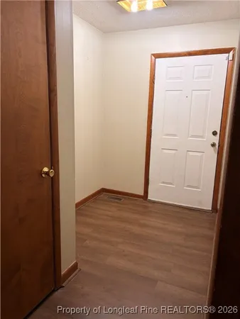a view of an empty room with wooden floor fireplace and a window