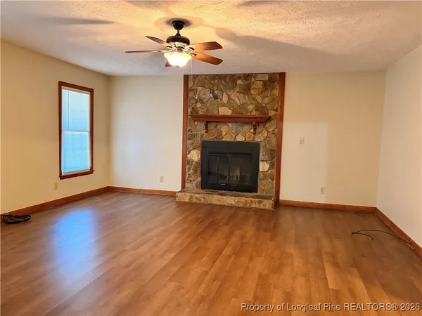 a view of an empty room with wooden floor and a fireplace