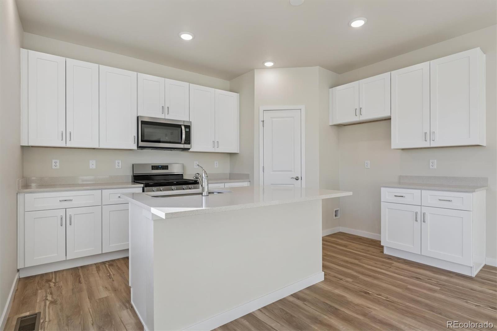 1430 Farmstead Street Brighton, CO 80601 - Photo 7 of 24 a kitchen with stainless steel appliances a refrigerator sink and white cabinets