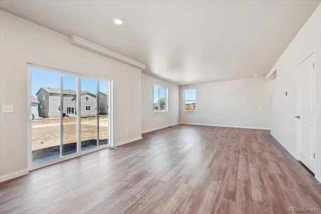 a view of an empty room with wooden floor and windows