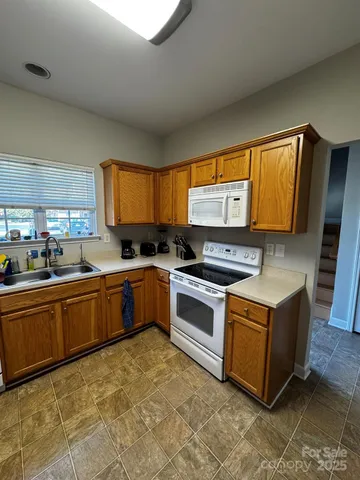 a kitchen with granite countertop a sink a counter top space stainless steel appliances and cabinets