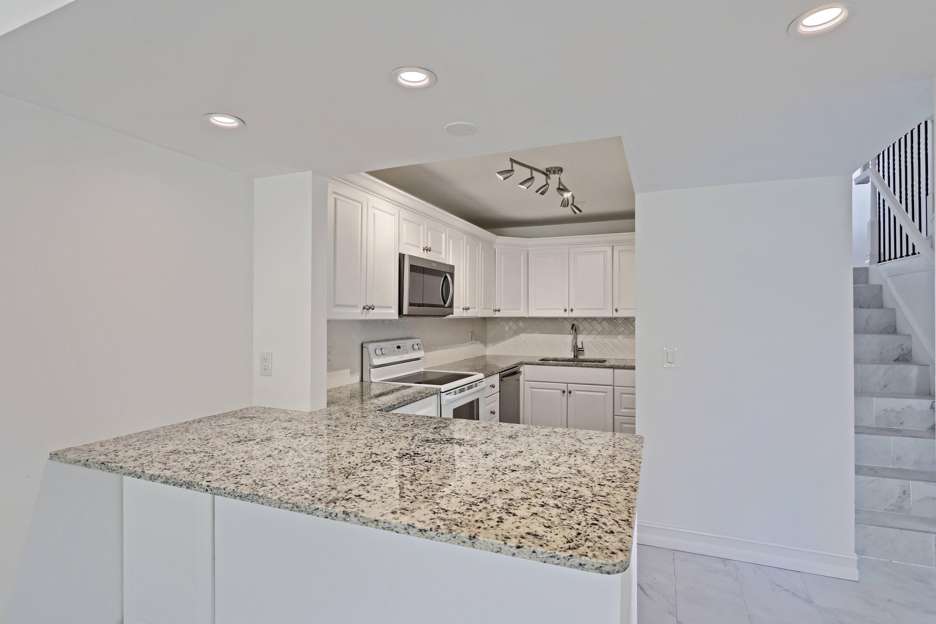 394 Golfview Road, Unit F North Palm Beach, FL 33408 - Photo 16 of 73 a kitchen with stainless steel appliances granite countertop a sink stove and cabinets
