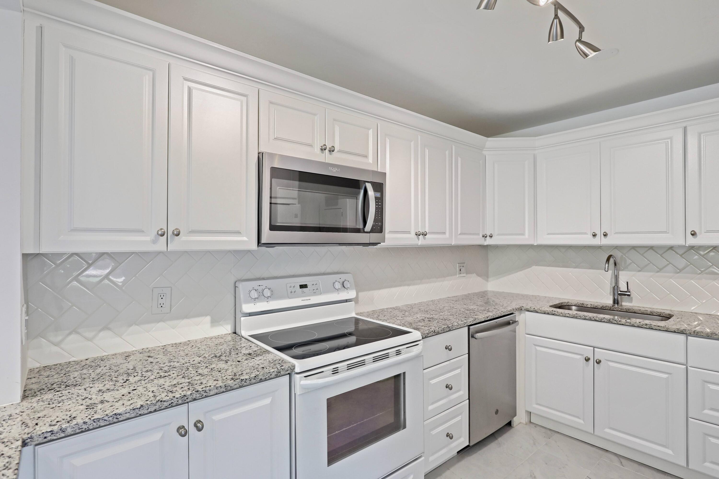 394 Golfview Road, Unit F North Palm Beach, FL 33408 - Photo 17 of 73 a kitchen with granite countertop white cabinets and white stainless steel appliances