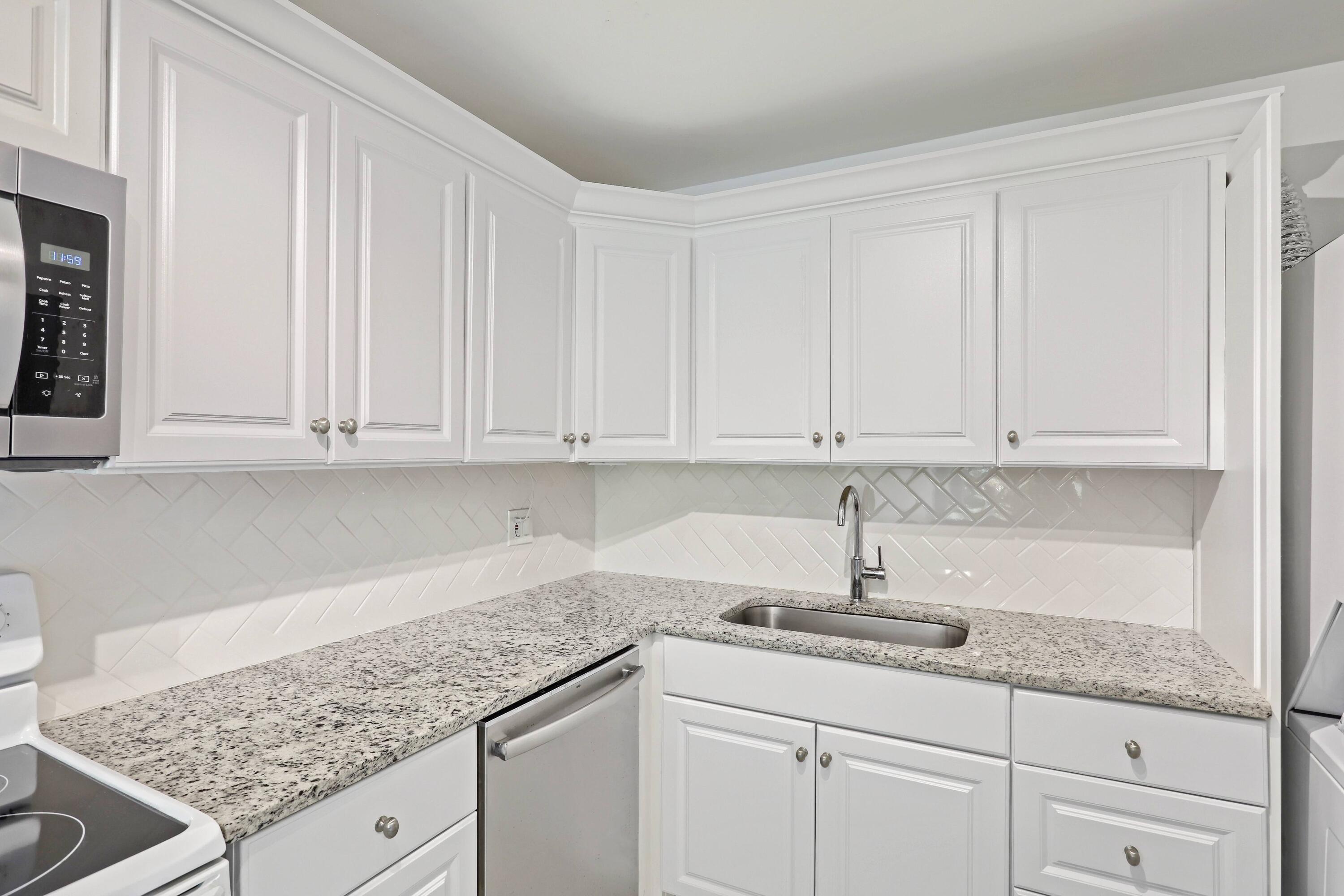 394 Golfview Road, Unit F North Palm Beach, FL 33408 - Photo 18 of 73 a kitchen with granite countertop white cabinets and sink