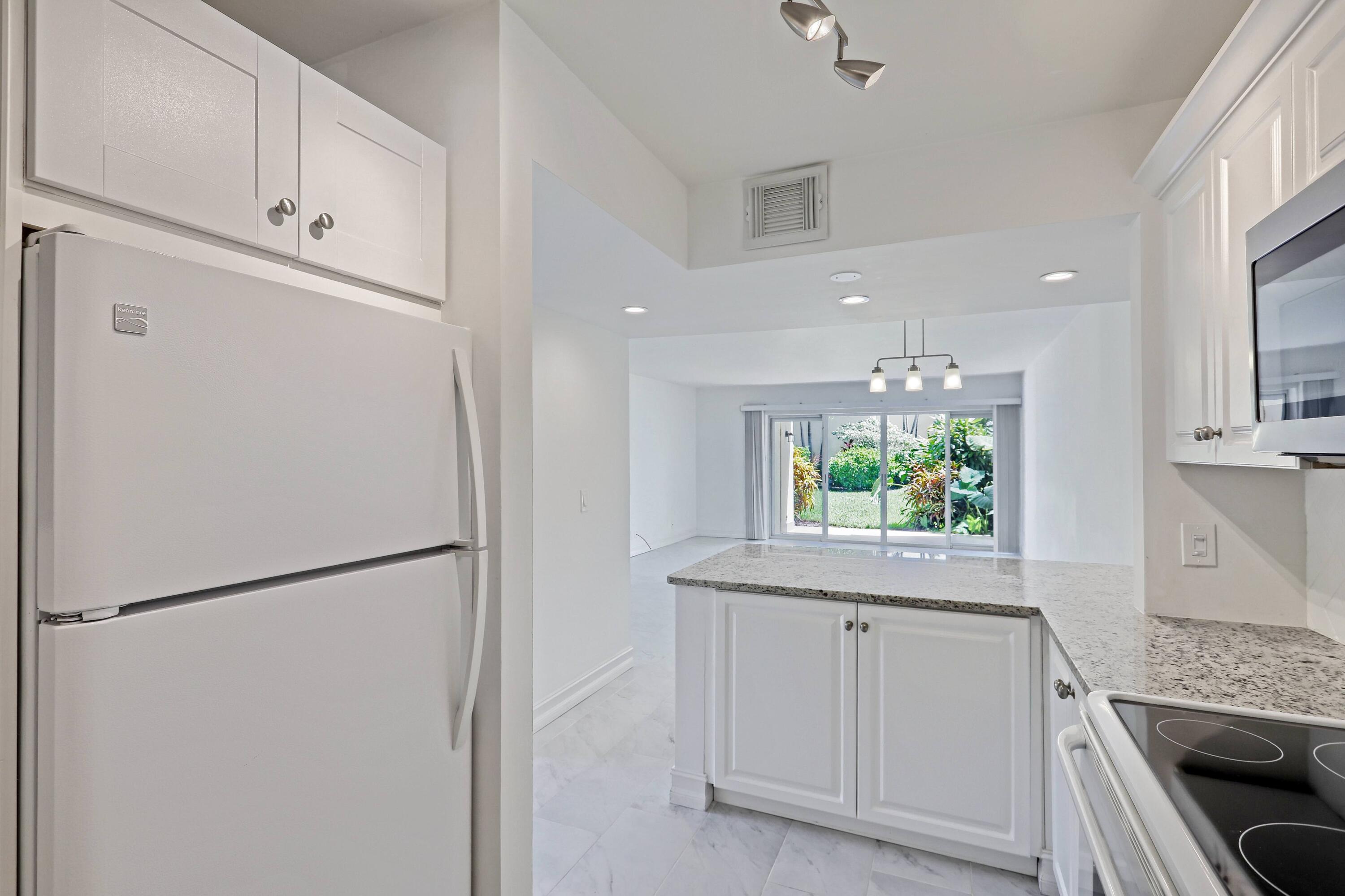 394 Golfview Road, Unit F North Palm Beach, FL 33408 - Photo 20 of 73 a kitchen with white cabinets and refrigerator