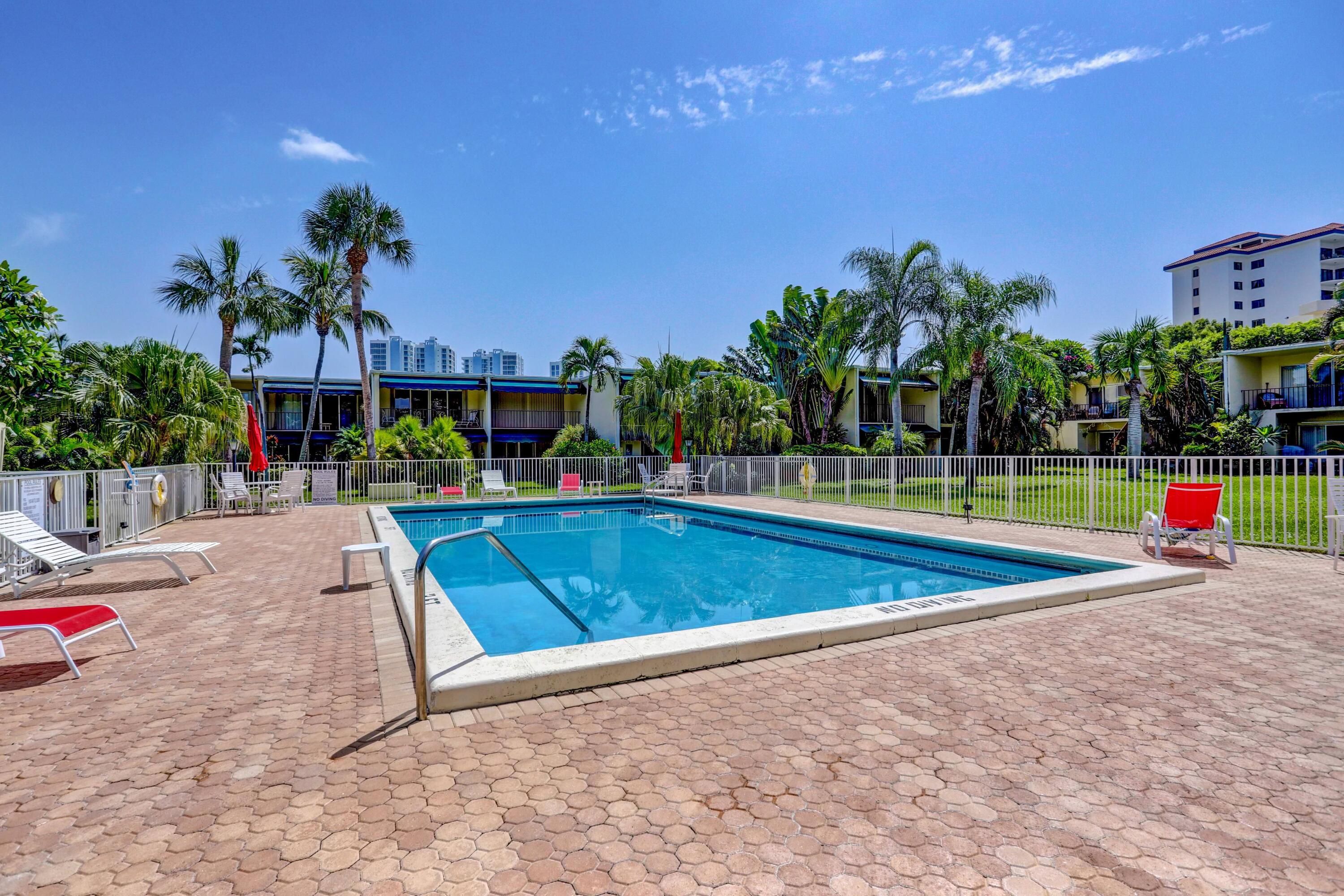 394 Golfview Road, Unit F North Palm Beach, FL 33408 - Photo 47 of 73 a view of a swimming pool with a yard and palm trees