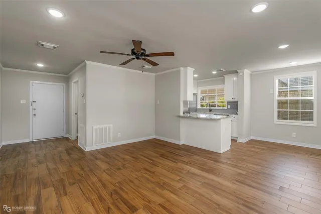 a kitchen with stainless steel appliances granite countertop a stove a sink dishwasher and white cabinets with wooden floor